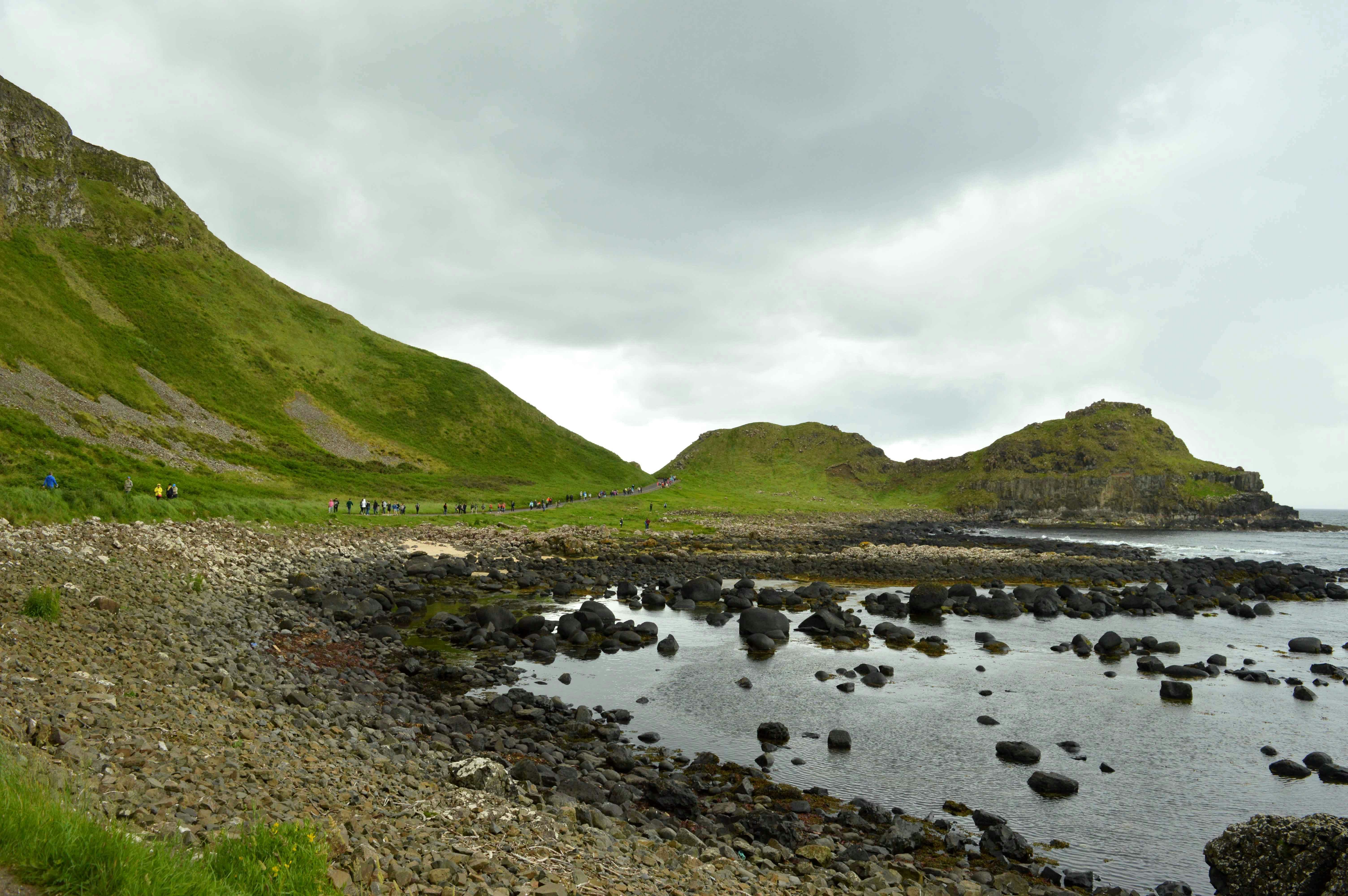 campo de grama verde perto do rio sob o céu nublado durante o dia