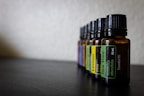 Glass vials of essential oils with herbs in the background.