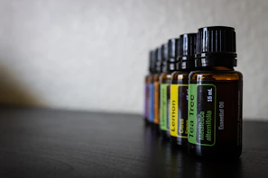 Close-up of amber-colored essential oils in glass bottles with wooden caps on a spa table