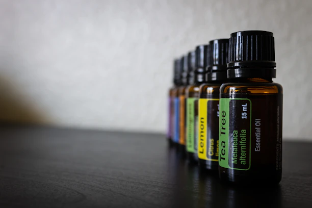 Close-up of amber glass bottles filled with essential oils arranged on a wooden table with botanical elements.