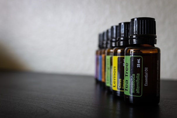 A close-up of amber glass bottles filled with various essential oils, softly lit to highlight their clarity.