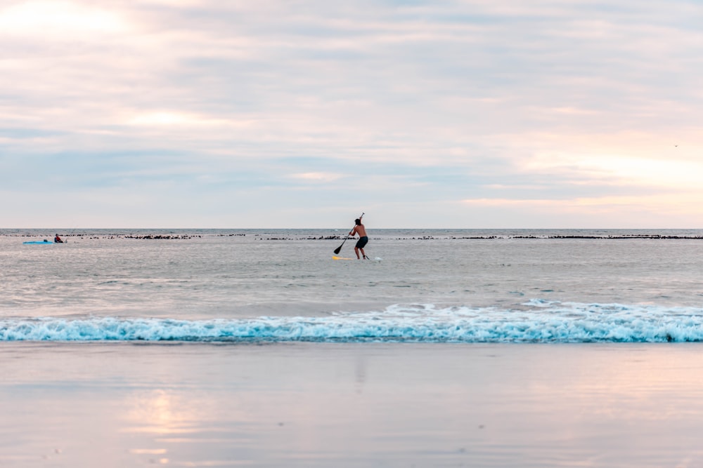 woman in black dress walking on beach during daytime