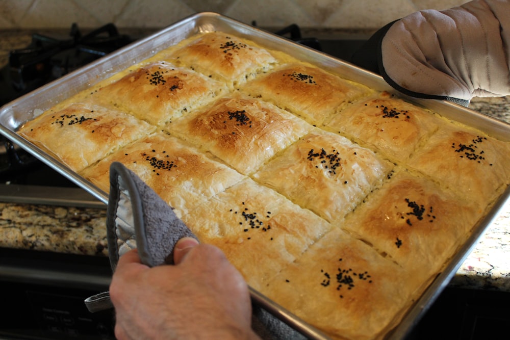 person holding stainless steel tray with pie