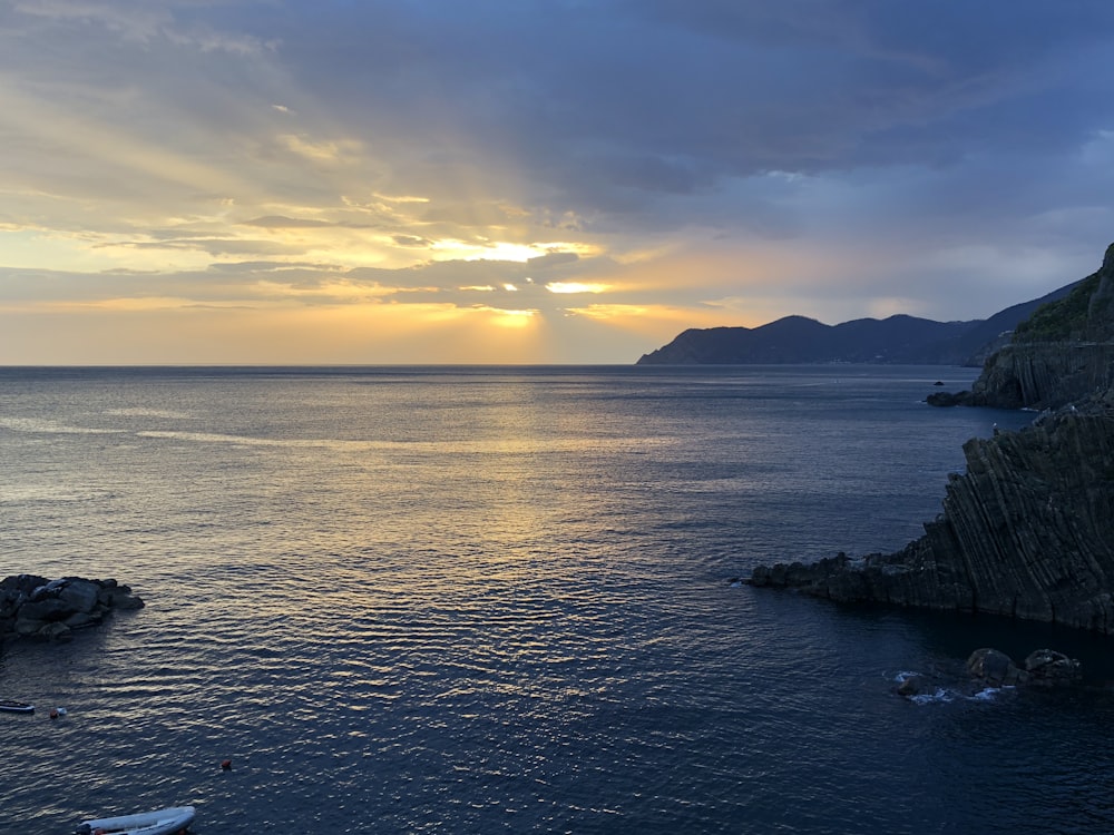 silhouette of mountain near body of water during sunset