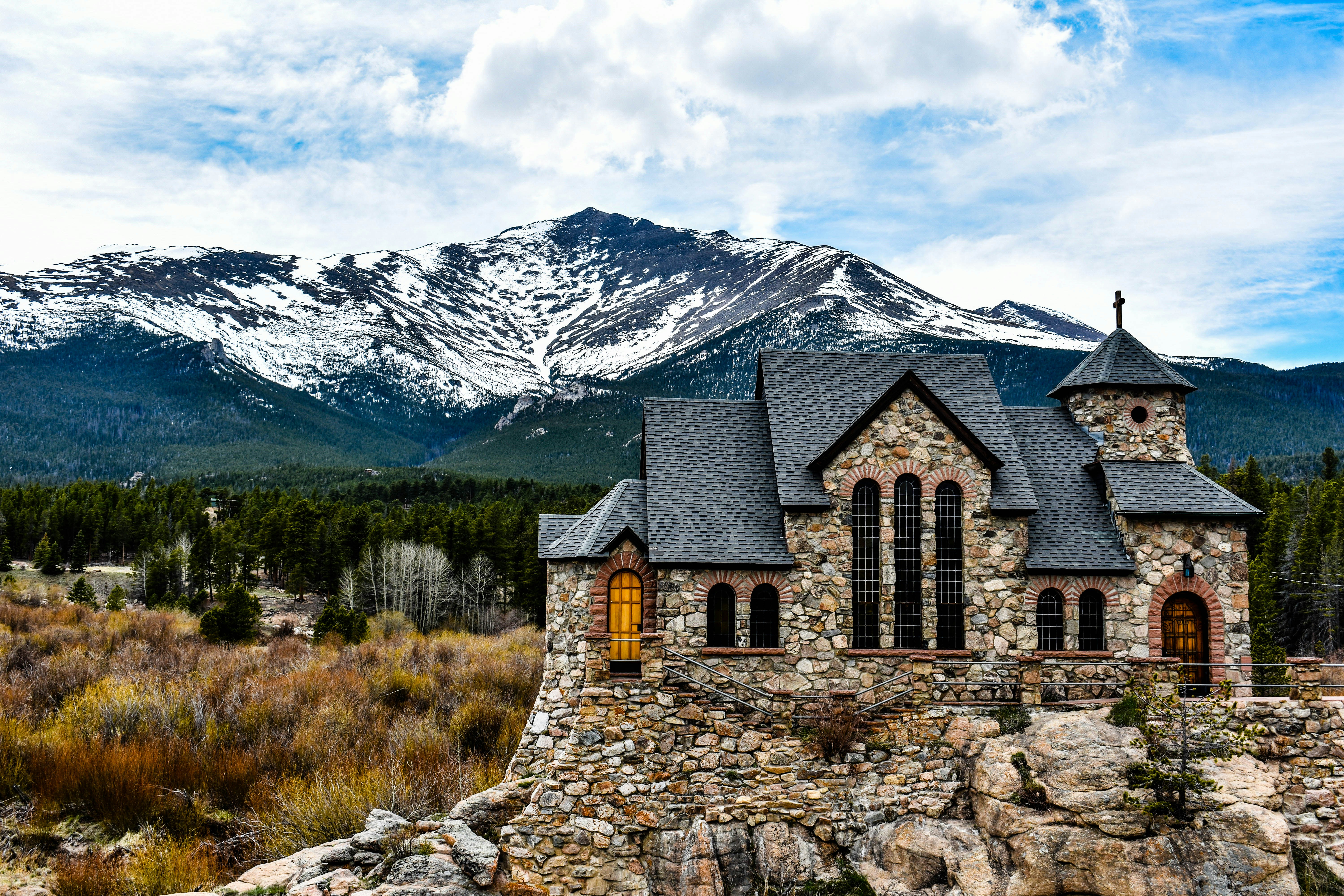 Braunes Backsteingebäude in Bergnähe tagsüber unter weißen Wolken