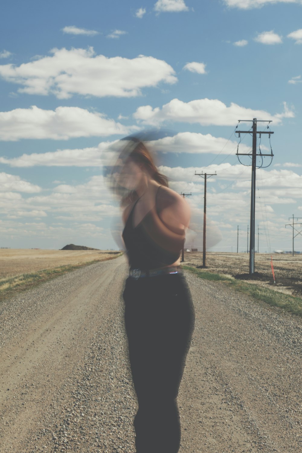 woman in black tank top standing on road during daytime