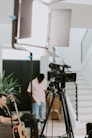 man in white dress shirt standing in front of black camera