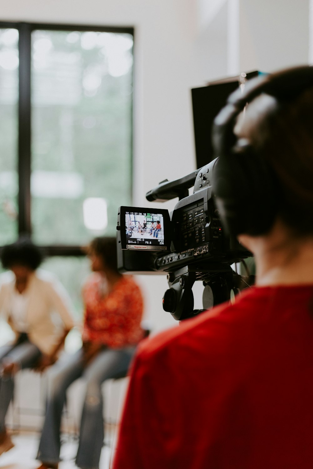 woman in red shirt holding black video camera