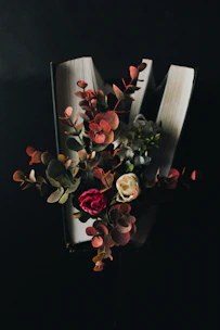 Close-up of hands flipping through a vibrant wellness book with fresh flowers nearby