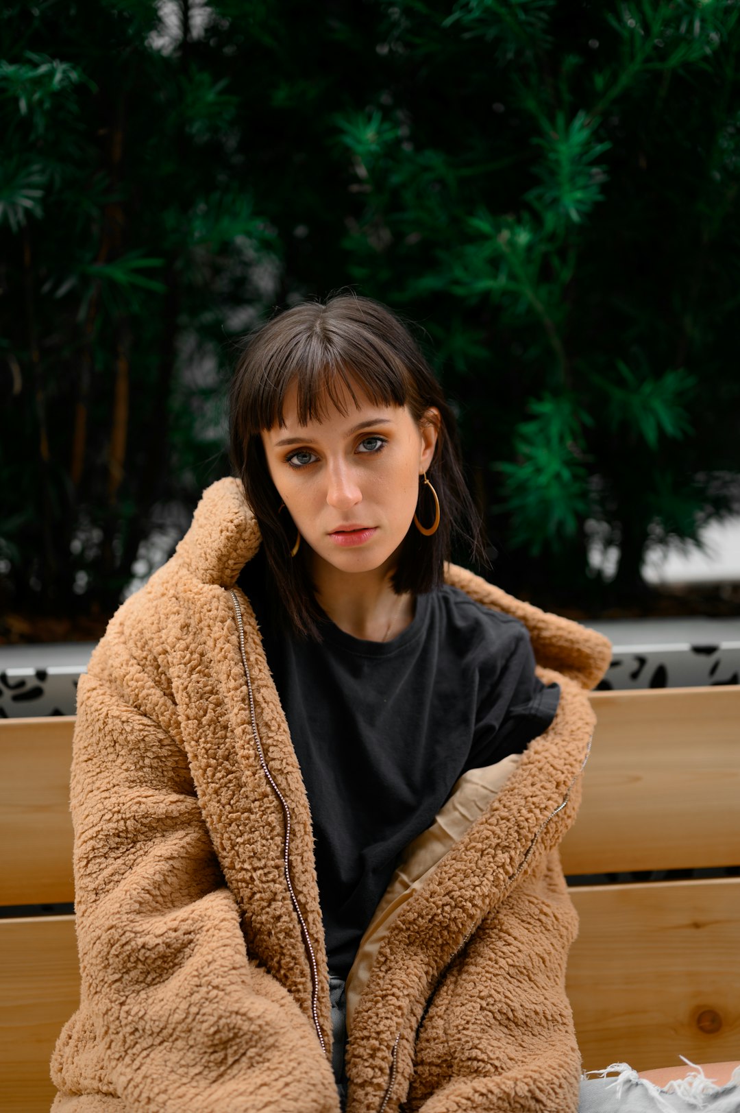 woman in brown cardigan sitting on brown wooden bench