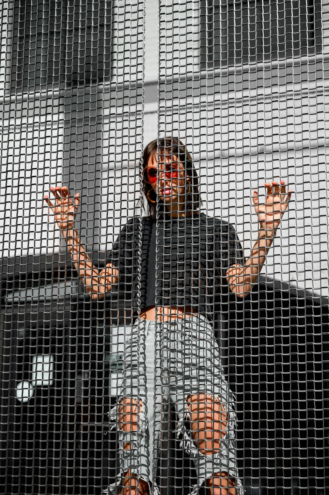 woman in black long sleeve shirt standing behind white metal fence