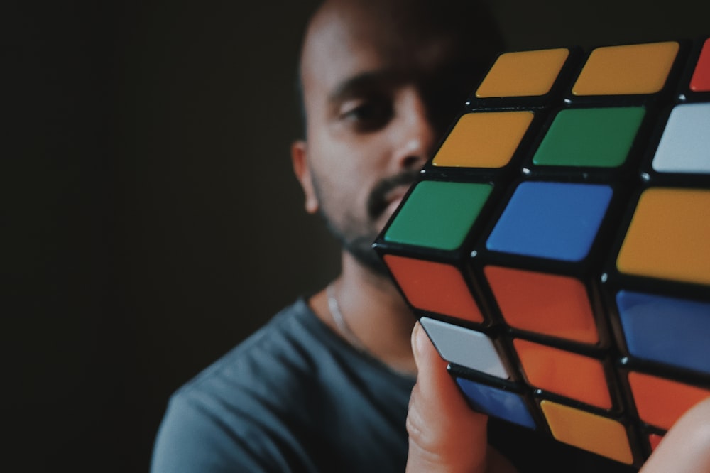 man in black crew neck t-shirt holding 3 x 3 rubiks cube