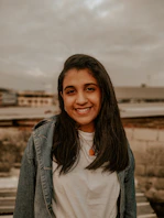 woman in white shirt and blue denim jacket smiling