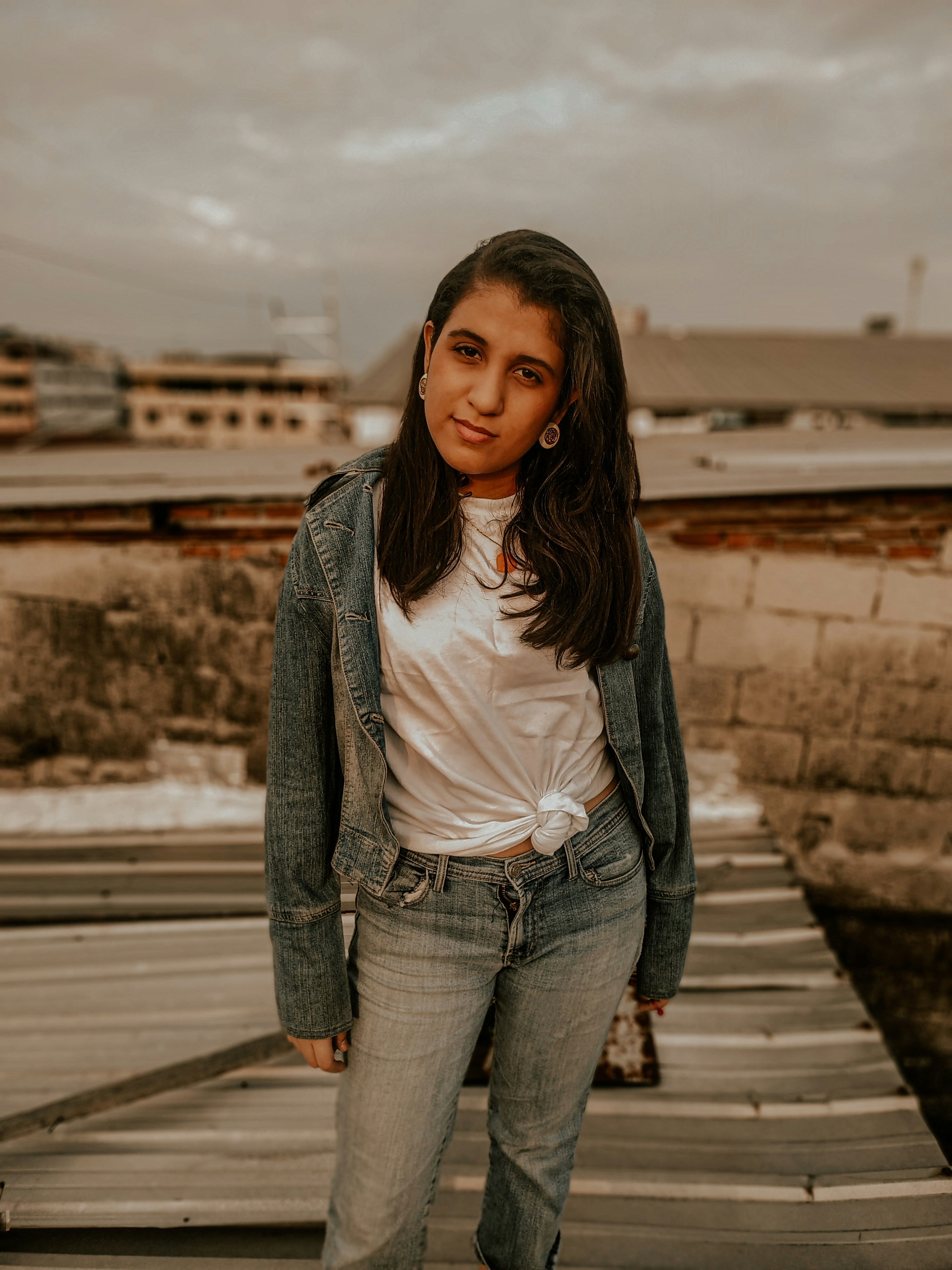woman in white shirt and gray cardigan standing on wooden dock during daytime
