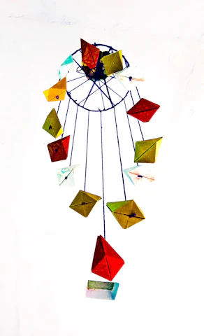 Close-up of a delicate champagne gold geometric mobile hanging against a soft cream wall.