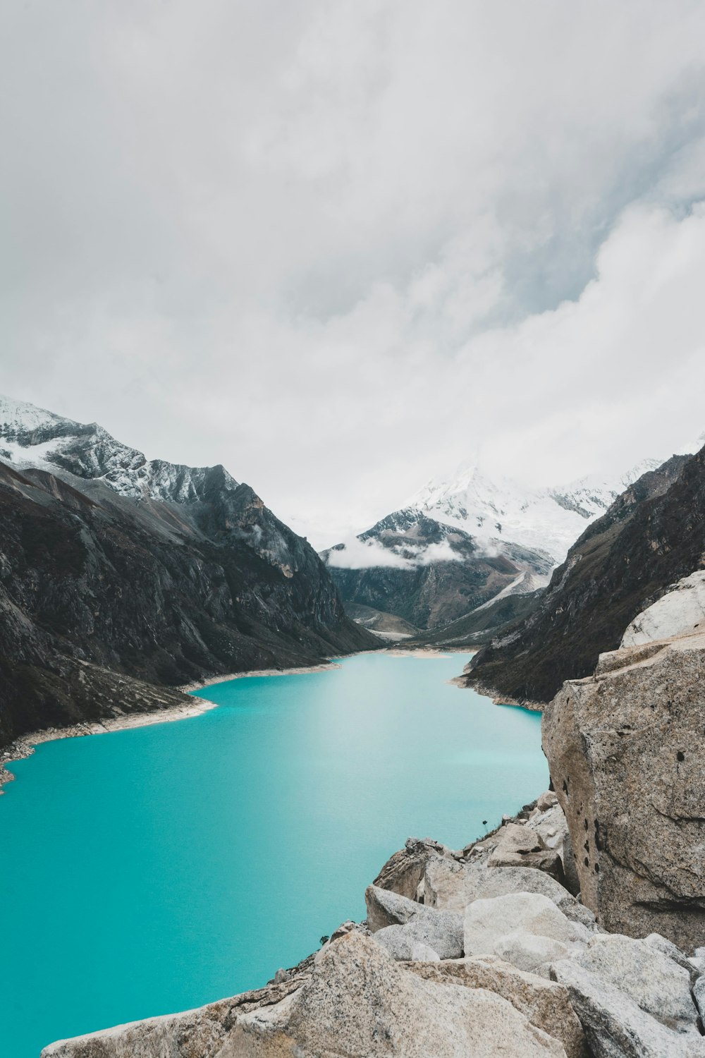 lago azul entre montanhas sob nuvens brancas e céu azul durante o dia