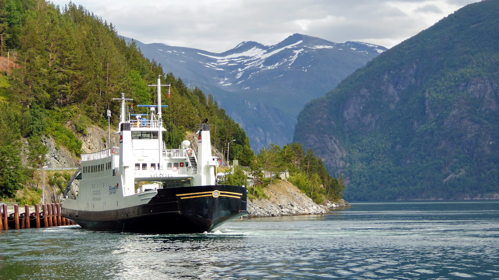 Ferry sailing on calm water with mountains behind