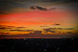 A vibrant sunset over the Dallas skyline with city lights beginning to twinkle.