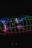Close-up of a glowing LED dance hoop spinning in the dark.
