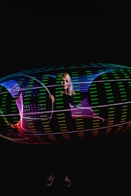 Character editing a vibrant glowing video hologram with neon accents.