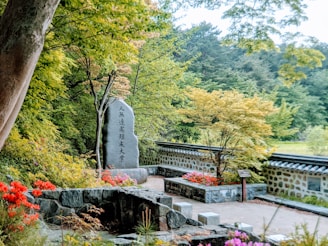 A peaceful garden scene with a memorial stone surrounded by greenery.