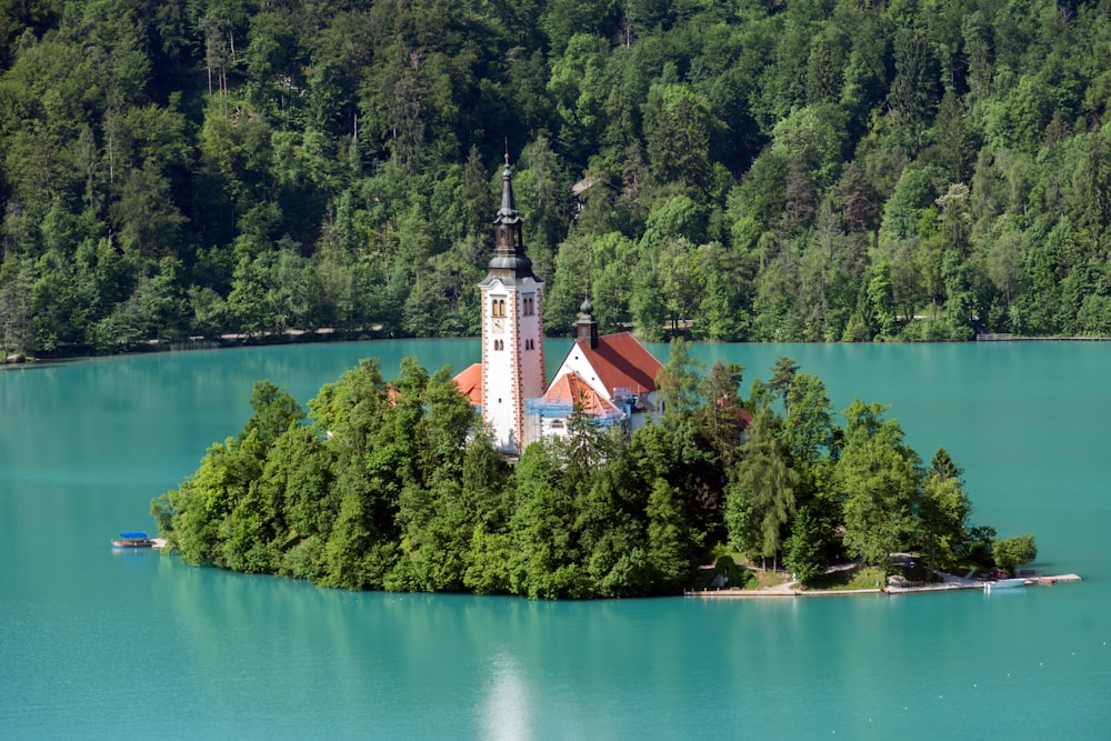 edificio in cemento bianco e marrone vicino agli alberi verdi e al lago durante il giorno