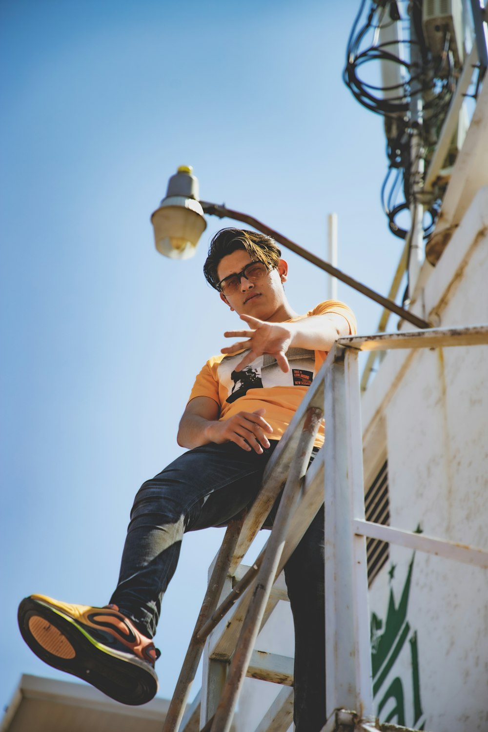 woman in black tank top and black pants sitting on white metal ladder during daytime