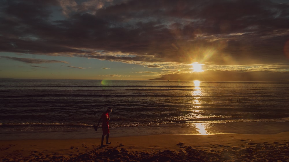 silhouette of woman standing on beach during sunset