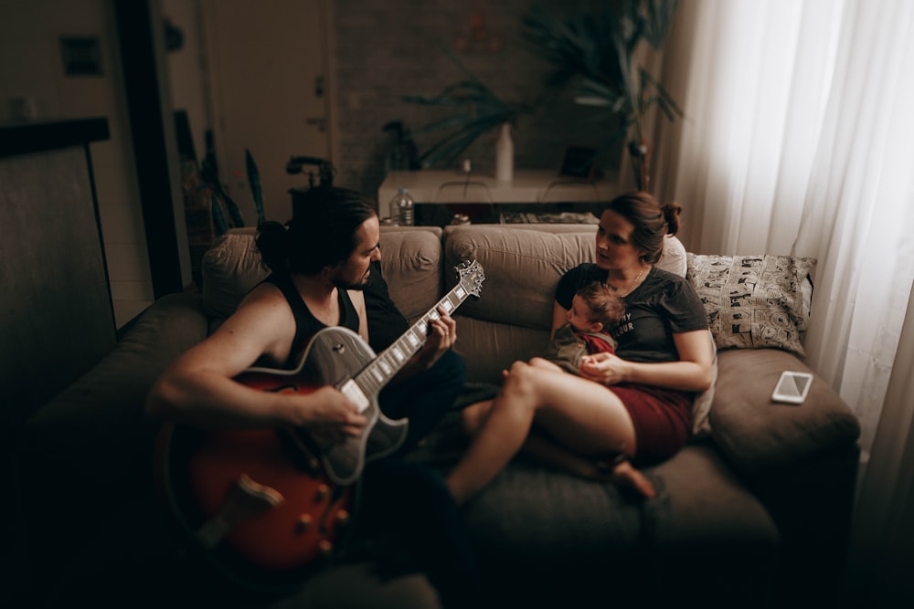 man playing guitar sitting beside woman