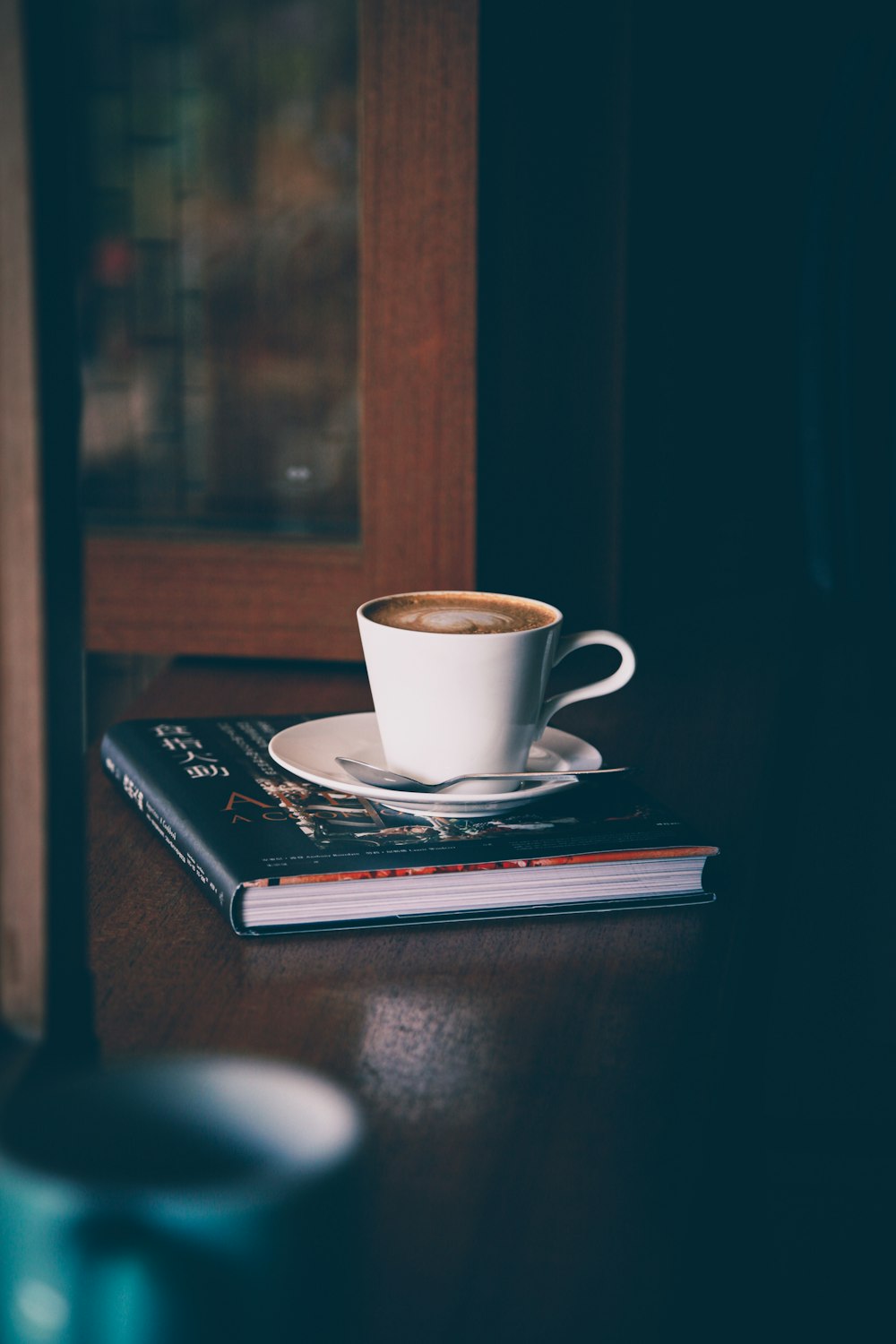 white ceramic mug on black and white book