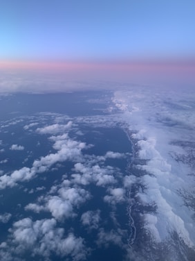 A breathtaking aerial view of Greenland’s icy coastline under a soft golden sunset.