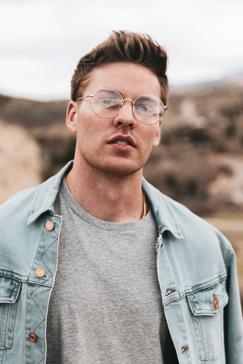 man in blue denim jacket wearing black framed eyeglasses