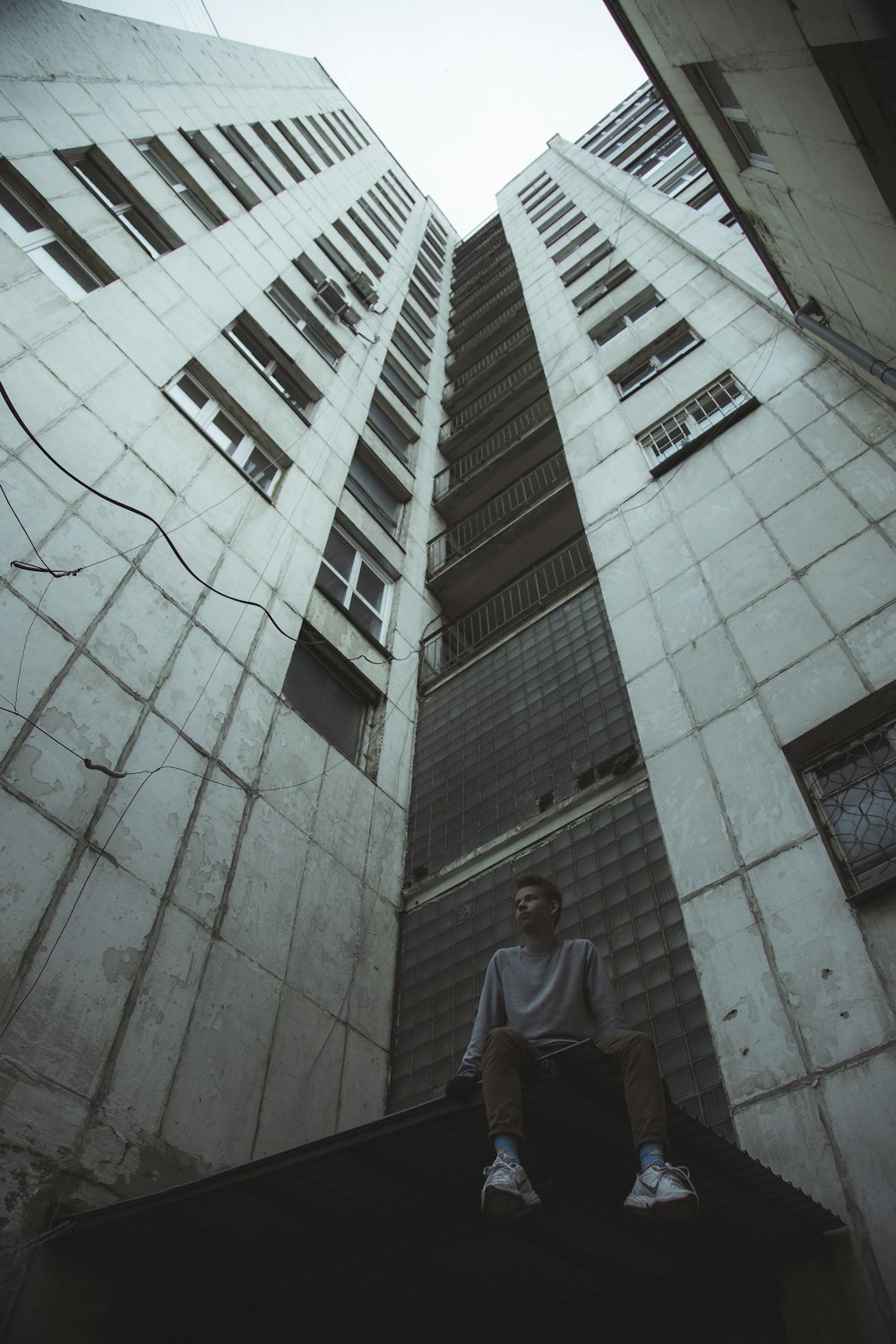 man in gray t-shirt standing near white concrete building during daytime