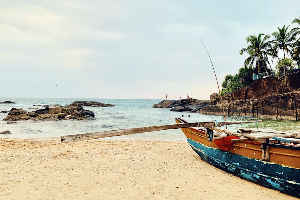 blue and red boat on beach during daytime