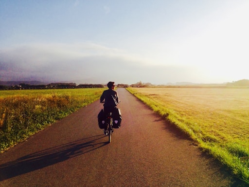 man in black jacket riding bicycle on road during daytime