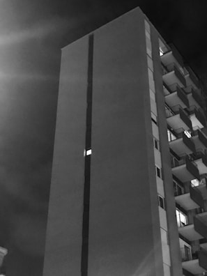 Evening shot of a high-rise building with illuminated balconies and cityscape backdrop.