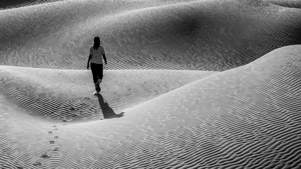 femme en veste noire marchant sur le sable