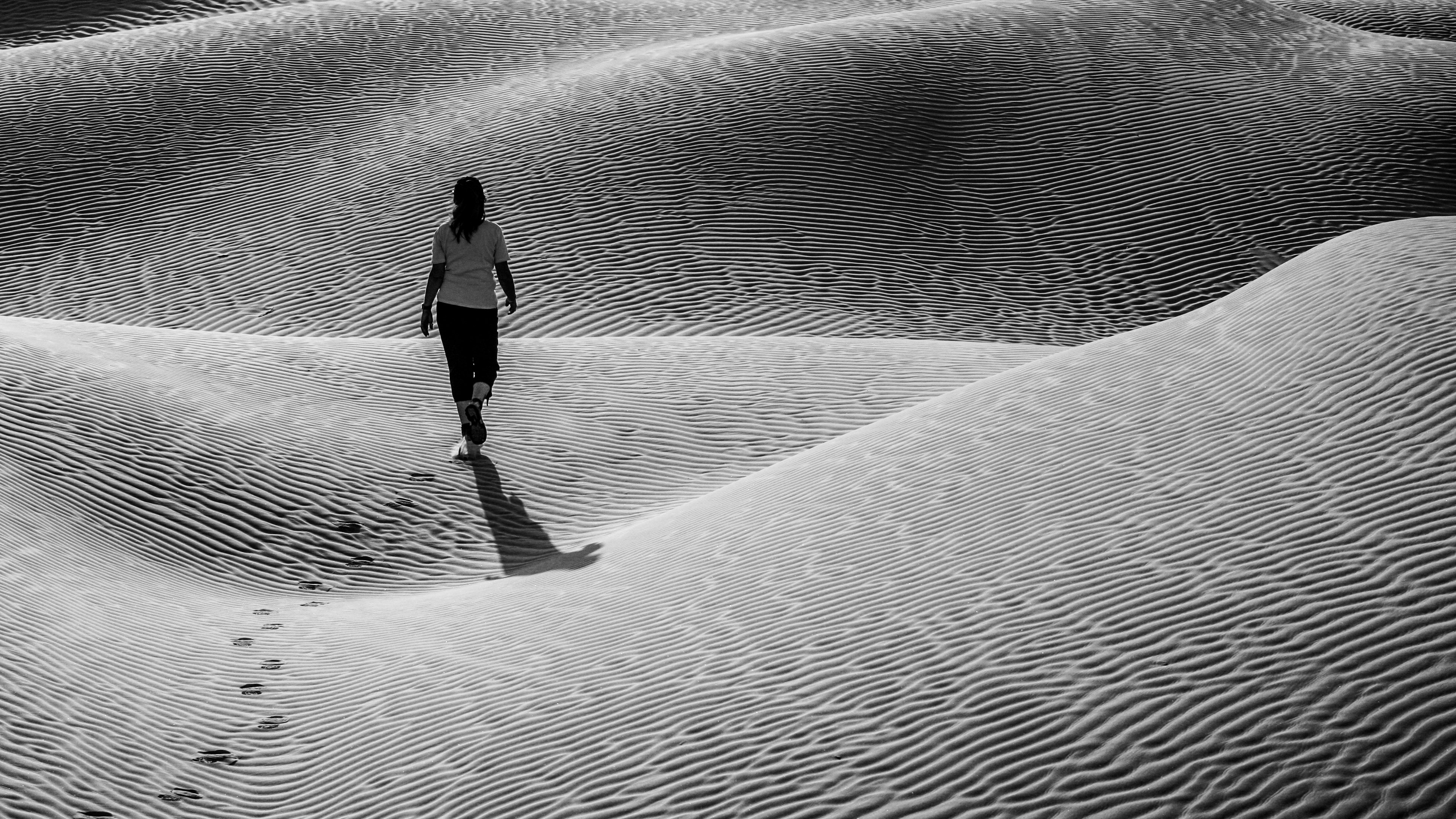 woman in black jacket walking on sand