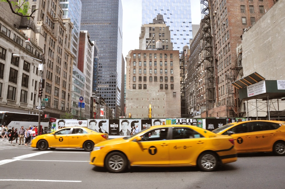 yellow taxi cab on road near high rise buildings during daytime