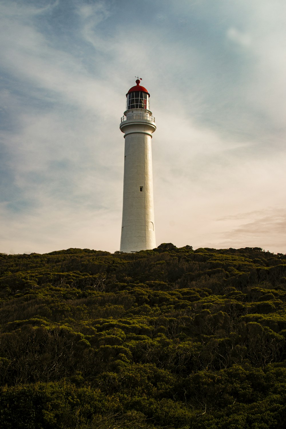 white and red lighthouse under cloudy sky during daytime