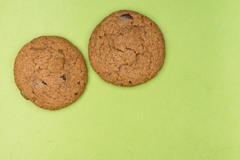 two brown cookies on green surface