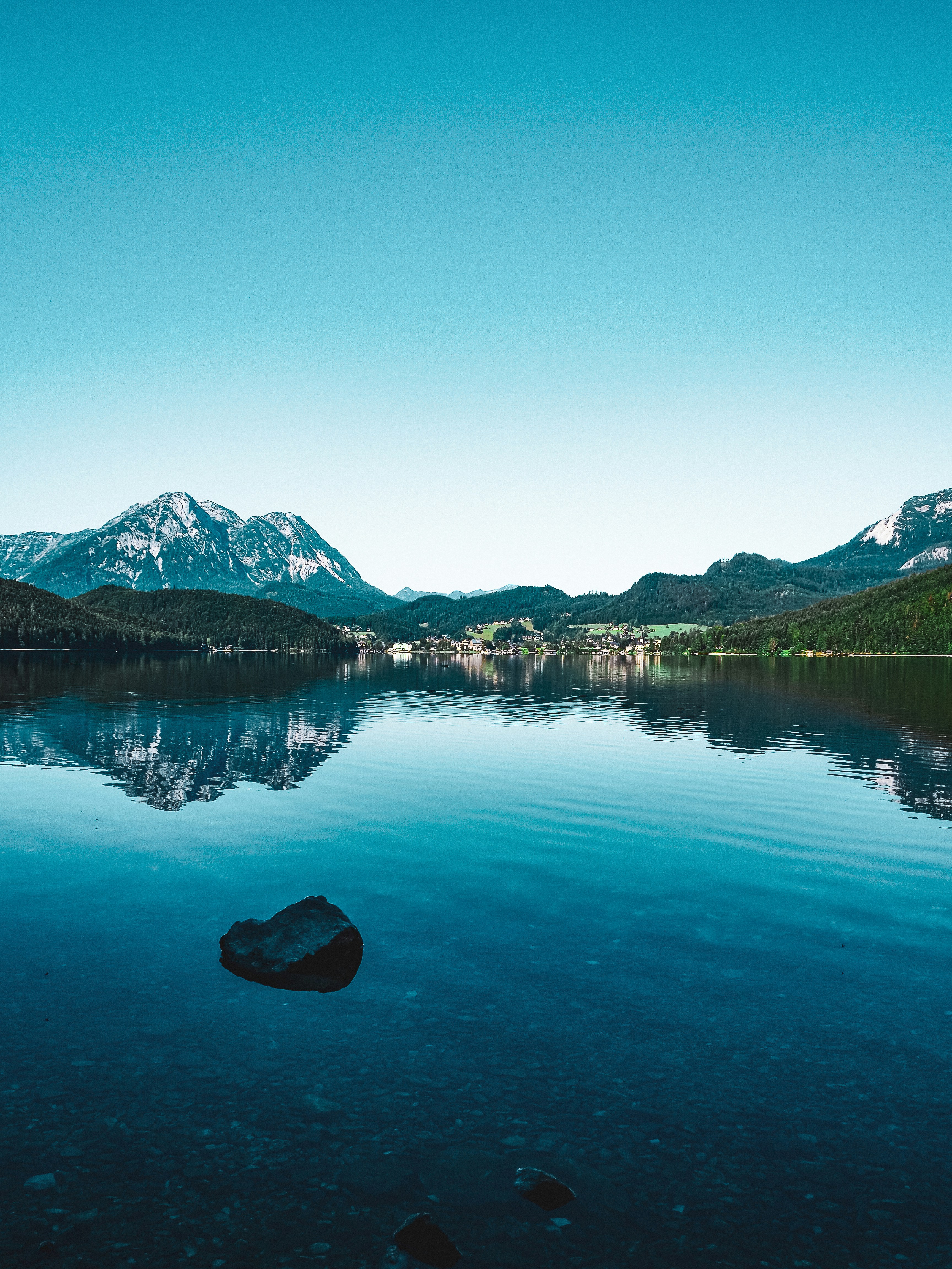 lake near mountain under blue sky during daytime