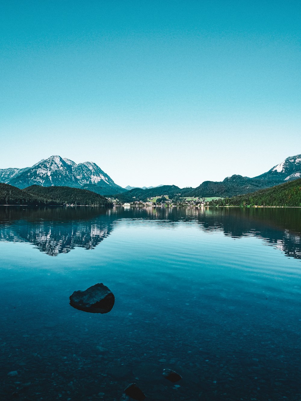 lake near mountain under blue sky during daytime