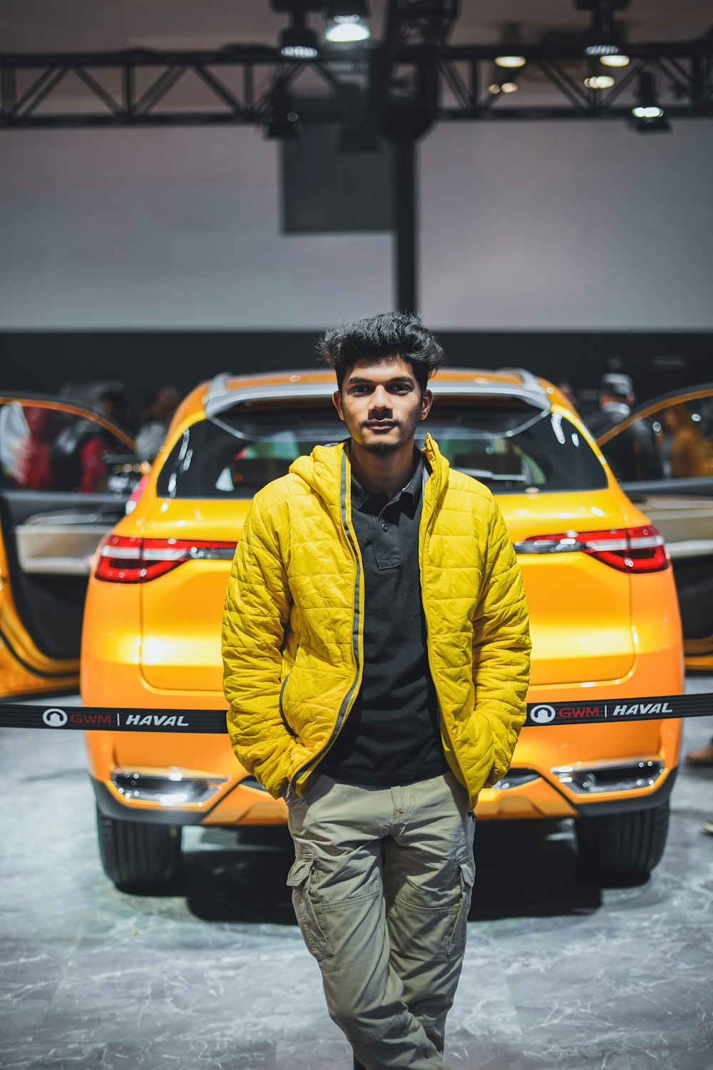 man in yellow zip up jacket standing beside orange car