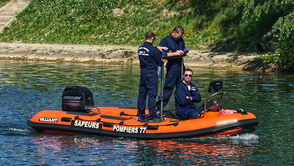 man in blue long sleeve shirt standing beside orange and black kayak