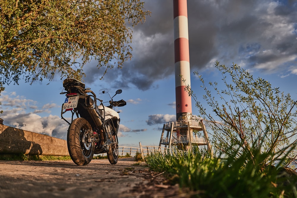 black motorcycle parked near red and white tower