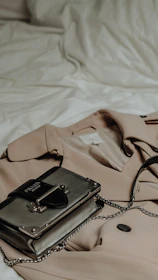 Close-up of a beige cashmere coat draped over a vintage leather armchair with subtle gold accents.