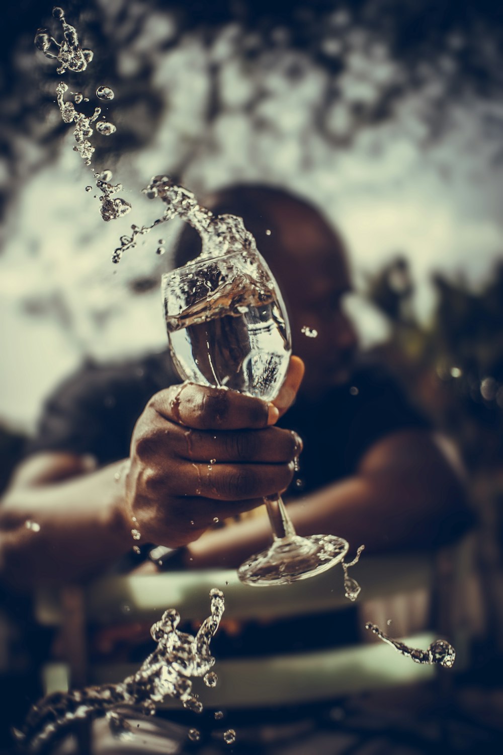 person holding clear wine glass with brown liquid