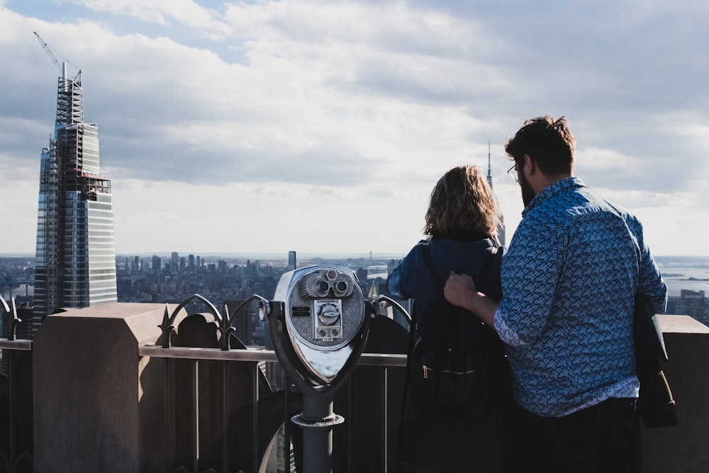 2 women standing on top of the building looking at the sea during daytime