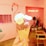 A hand holding a cone of chocolate ice cream, adorned with colorful sprinkles and a cookie, is in focus. The background features a pink-themed interior with potted plants, a flamingo mural, and a neon sign that reads 'Pinkholic Café'.